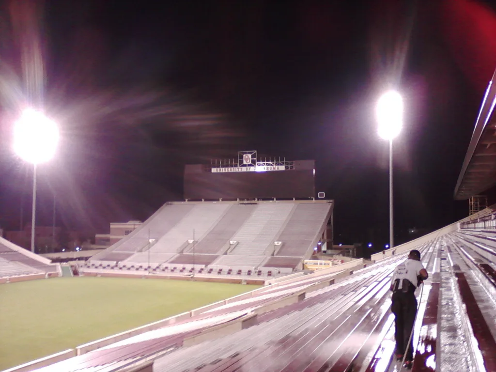 Commercial pressure washing service cleaning stadium bleachers and concrete seating in Norman Oklahoma - Nighttime field view