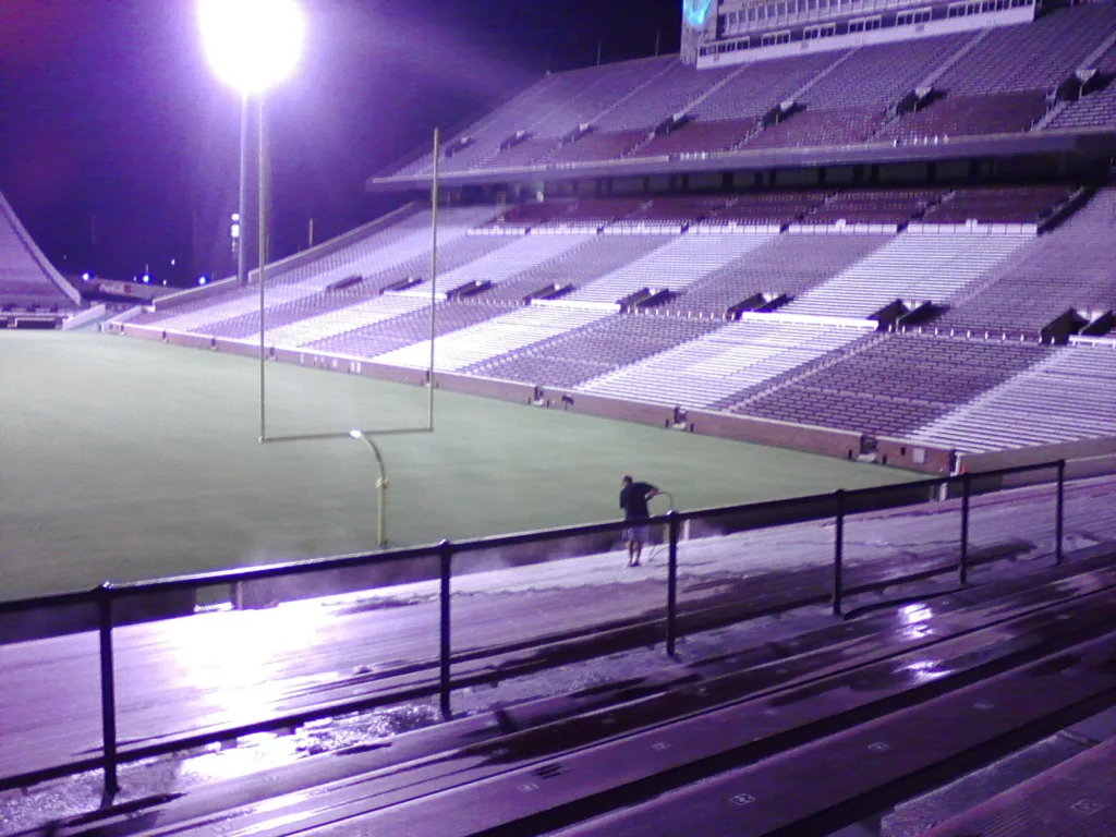 Commercial pressure washing service cleaning stadium bleachers and concrete seating in Norman Oklahoma - Active spray cleaning