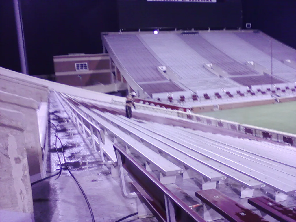 Commercial pressure washing service cleaning stadium bleachers and concrete seating - Upper deck perspective