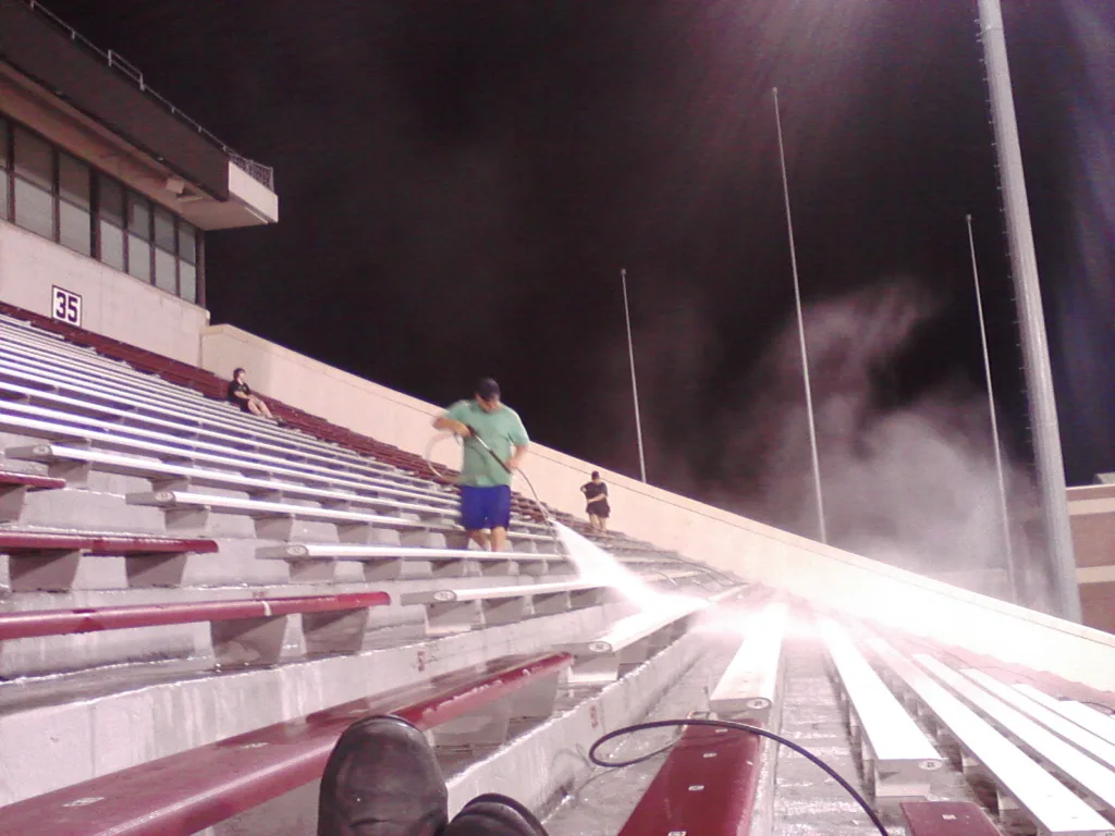 Commercial pressure washing service cleaning stadium bleachers and concrete seating in Norman Oklahoma - Bleacher row perspective