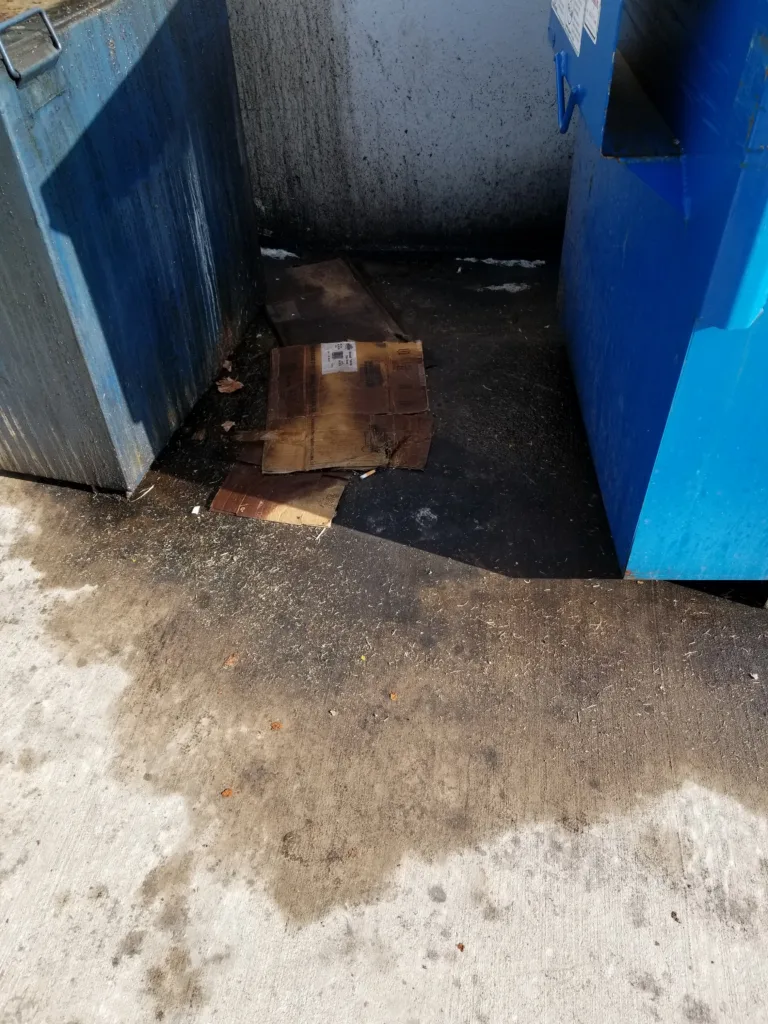 Commercial pressure washing service cleaning dirty oil and grease from dumpster pad concrete - Before transformation"