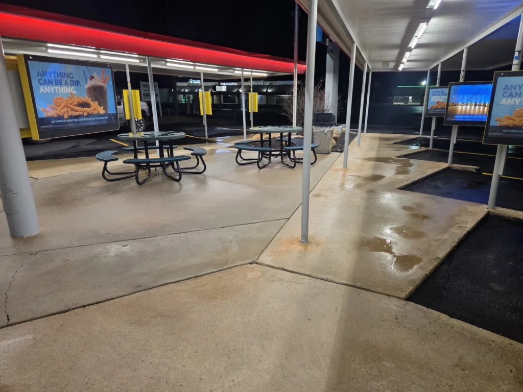 Commercial pressure washing service cleaning fast food patio concrete and walkways at night